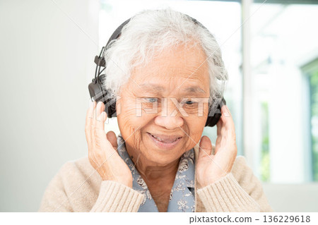 Asian senior woman patient happy to use earphone to listen relax music. Asian senior woman patient happy to use earphone to listen relax music. 136229618