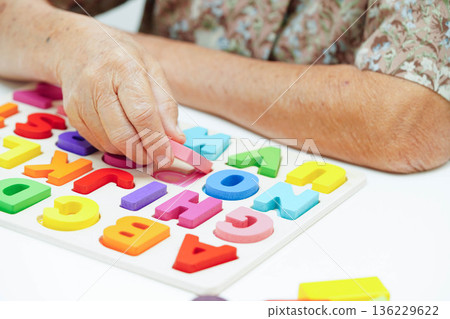 Asian elderly woman playing enhancing skill board game. 136229622