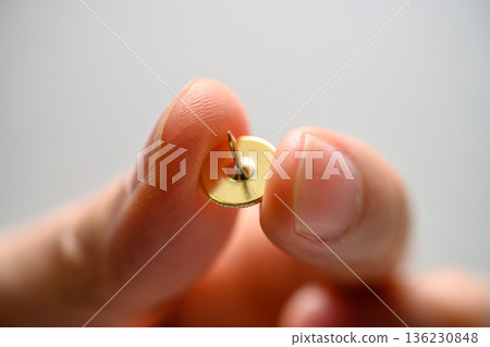 thumbtack held by finger 136230848