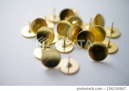 Golden thumbtacks on the desk 136230867