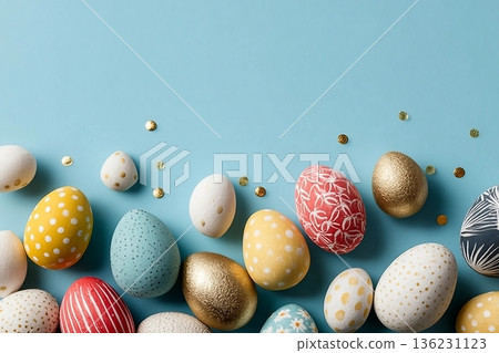 Assorted colored decorative Easter eggs laid out on a light blue surface, with various patterns and textures 136231123