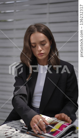 Young stylish woman reading a fashion magazine outdoors at a cafe Young stylish woman reading a fashion magazine outdoors at a cafe 136232317