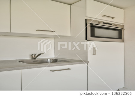 A sleek and contemporary kitchen featuring white cabinetry, stainless steel appliances, and a clean countertop. Ideal for modern living spaces. 136232505