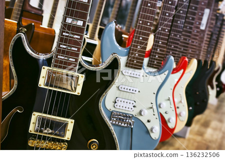 A collection of electric solid body guitars hanging in a row A collection of electric solid body guitars hanging in a row 136232506