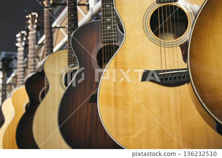 A collection of Taylor brand acoustic guitars hanging in a row 136232510
