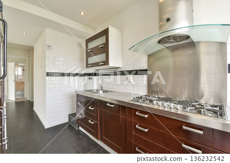 Stylish and contemporary kitchen showcasing sleek cabinetry, stainless steel appliances, and minimalist aesthetics. A blend of functionality and elegance. Stylish and contemporary kitchen showcasing sleek cabinetry, stainless steel appliances, and minimalist aesthetics. A blend of functionality and elegance. 136232542