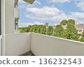 A well-designed balcony with a view of vibrant green trees and urban architecture in the background. Ideal for relaxation and enjoying nature in an urban setting. 136232543