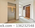 A sleek entrance hallway featuring an elevator and a wooden door, modern design elements, and smooth flooring create a welcoming atmosphere. 136232548