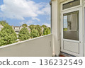 A view from a balcony showcasing a well-maintained residential area with green trees and a clear blue sky. 136232549