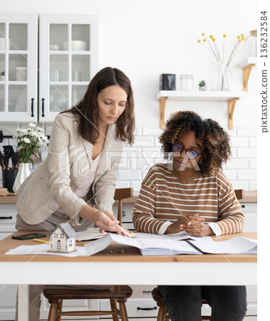 business person sitting at table, negotiating. two women going through papers, discussing project. business person sitting at table, negotiating. two women going through papers, discussing project. 136232584