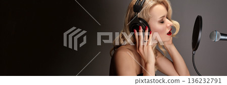 Female Singer In Recording Studio, Glamorous Session Vocalist Recording Pop Ballad Into Condenser Microphone, Wearing Large Headphones And Retro Makeup, Dramatic LowKey, Indie Artist, Pop Music Song Female Singer In Recording Studio, Glamorous Session Vocalist Recording Pop Ballad Into Condenser Microphone, Wearing Large Headphones And Retro Makeup, Dramatic LowKey, Indie Artist, Pop Music Song 136232791