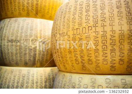Close-up shot of whole cheese wheels stacked in a pile - genuine DOP (Protected Designation of Origin) Parmigiano Reggiano parmesan Close-up shot of whole cheese wheels stacked in a pile - genuine DOP (Protected Designation of Origin) Parmigiano Reggiano parmesan 136232932