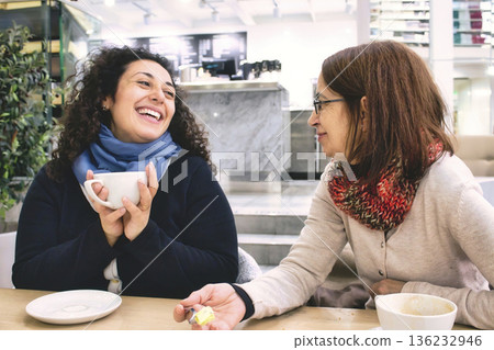 Two women of different generations having a good time enjoying a cup of coffee in a cafeteria 136232946