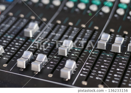 A close-up shot of grooved fader balance buttons on a mixing desk in a professional recording studio, selective focus with blurred background 136233156
