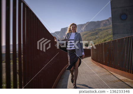 Woman fashion walking stylish professional on modern bridge with mountain background Woman fashion walking stylish professional on modern bridge with mountain background 136233346
