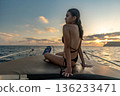 Woman boat sunset, young woman sitting on boat enjoying serene ocean sunset view during summer vacation 136233471