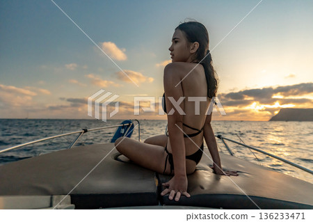 Woman boat sunset, young woman sitting on boat enjoying serene ocean sunset view during summer vacation Woman boat sunset, young woman sitting on boat enjoying serene ocean sunset view during summer vacation 136233471