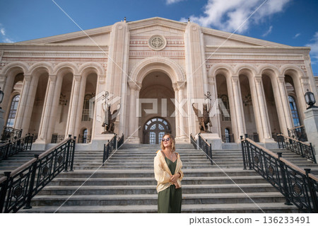 Woman Standing Building Azerbaijan - A woman stands in front of a grand building with columns in Azerbaijan. Woman Standing Building Azerbaijan - A woman stands in front of a grand building with columns in Azerbaijan. 136233491