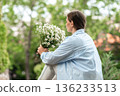 Daisies Bouquet Woman Nature: Summer day, woman sits, holding daisies, outdoors, enjoying peaceful moment in garden. 136233513