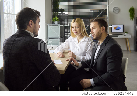 Financial advisor consulting couple clients during private meeting in office 136234442