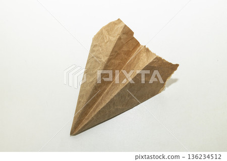 The homemade plane made from old vintage torn brown paper on white background The homemade plane made from old vintage torn brown paper on white background 136234512