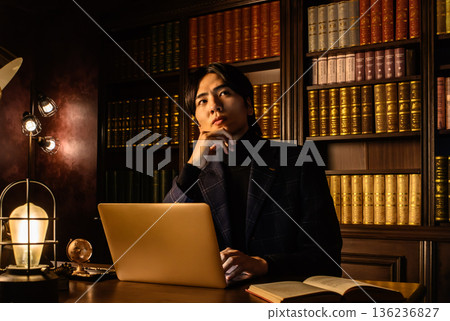 一位穿著西裝的年輕日本男子在他的書房裡沉思。 136236827