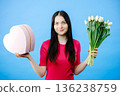 Girl holding in hands tulips and giftbox, isolated over blue background 136238759