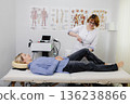 Doctor examining patient knee reflex with hammer 136238866