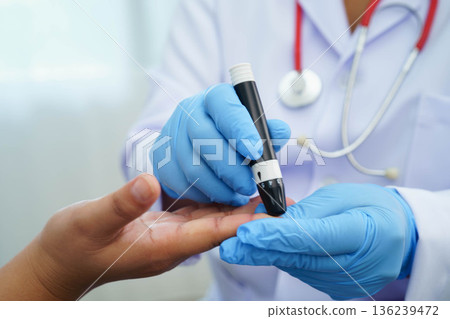 Doctor check diabetes from finger blood sugar level with finger lancet. Doctor check diabetes from finger blood sugar level with finger lancet. 136239472