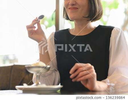 一位微笑的年輕女子在咖啡館吃冰淇淋(半身像) 一位微笑的年輕女子在咖啡館吃冰淇淋(半身像) 136239864