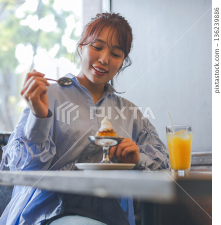 Asian woman eating pudding a la mode at a cafe 136239886