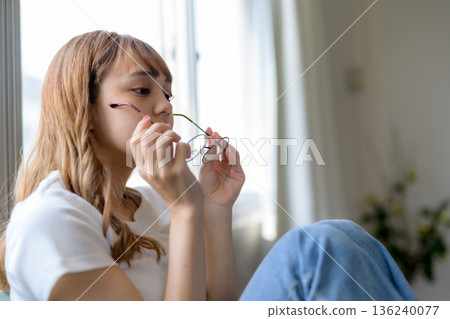 A woman takes off her glasses A woman takes off her glasses 136240077