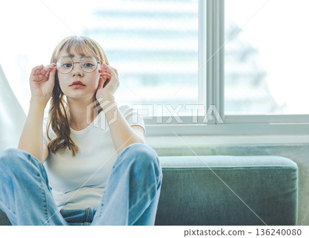 A woman with round glasses sits 136240080