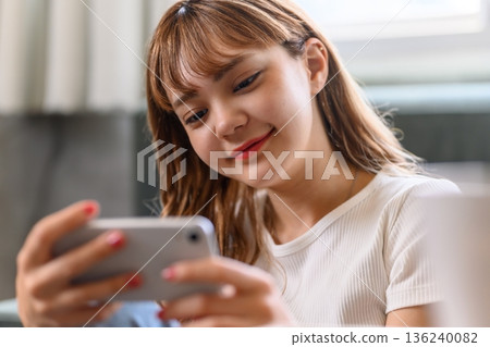 Young woman looking at a smartphone Young woman looking at a smartphone 136240082