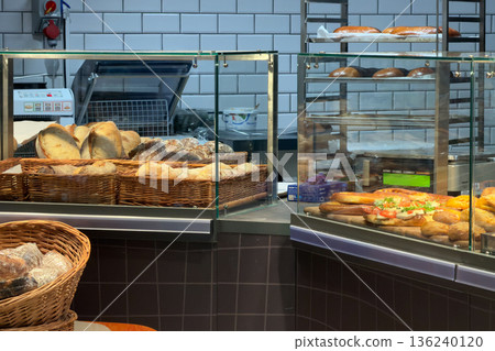 Vibrant bakery display case showcasing fresh artisanal bread loaves, diverse gourmet sandwiches, and a prominent container of cottage cheese, emphasizing daily food retail Vibrant bakery display case showcasing fresh artisanal bread loaves, diverse gourmet sandwiches, and a prominent container of cottage cheese, emphasizing daily food retail 136240120