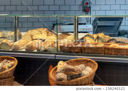 Freshly baked artisanal bread loaves displayed in a contemporary bakery counter and rustic baskets, emphasizing wholesome food and daily sustenance Freshly baked artisanal bread loaves displayed in a contemporary bakery counter and rustic baskets, emphasizing wholesome food and daily sustenance 136240121