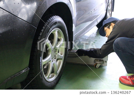 一名男子正在更換輪胎並進行檢查和維護。 136240267