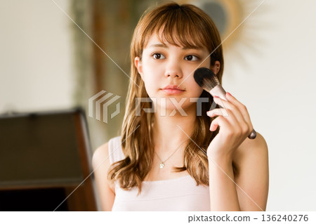 A woman applies makeup 136240276