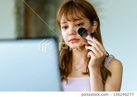 A woman applies makeup A woman applies makeup 136240277