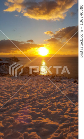 A stunning sunrise casts golden light over a snowy coastline in the Kuril Islands. 136240380
