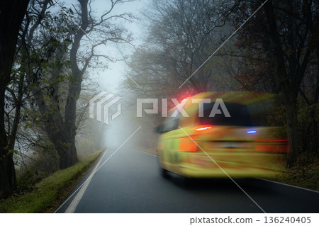 Emergency ambulance speeding on road in heavy fog on gloomy autumn day 136240405