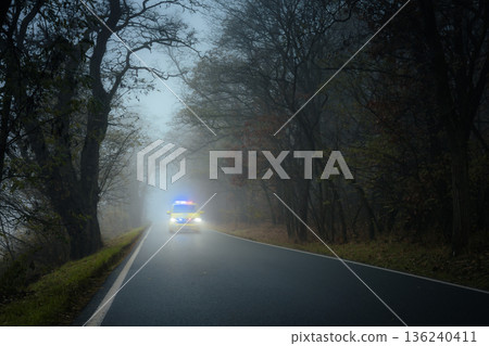 Emergency ambulance speeding on road in heavy fog 136240411