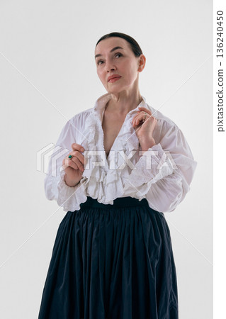 Classic woman in white ruffled blouse posing in studio portrait. 136240450