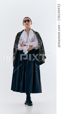 Mature woman in white ruffled blouse and long skirt posing. 136240452