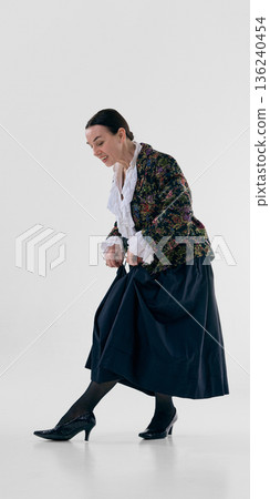 Mature woman in floral jacket showcasing elegant high heel shoe. 136240454