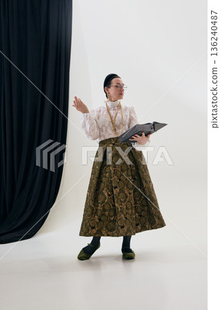 Elegant mature woman reading book in classic poetcore outfit. 136240487