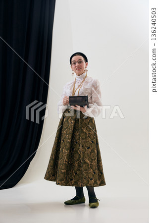 Vintage poetcore woman holding notebook in studio portrait with thoughtful calm. 136240503