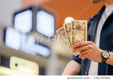 A man presents Japanese yen. Photo courtesy of Kansai International Airport (KIX) 136240986