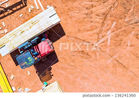 Tractor is transporting wooden planks at construction site scattered across Tractor is transporting wooden planks at construction site scattered across 136241360