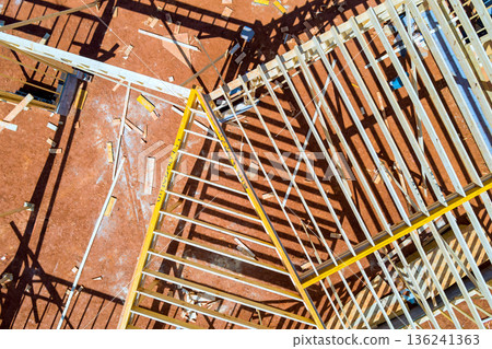 Workers are building wooden frame beams structure with pieces of wood roofing joist scattered across construction site. 136241363